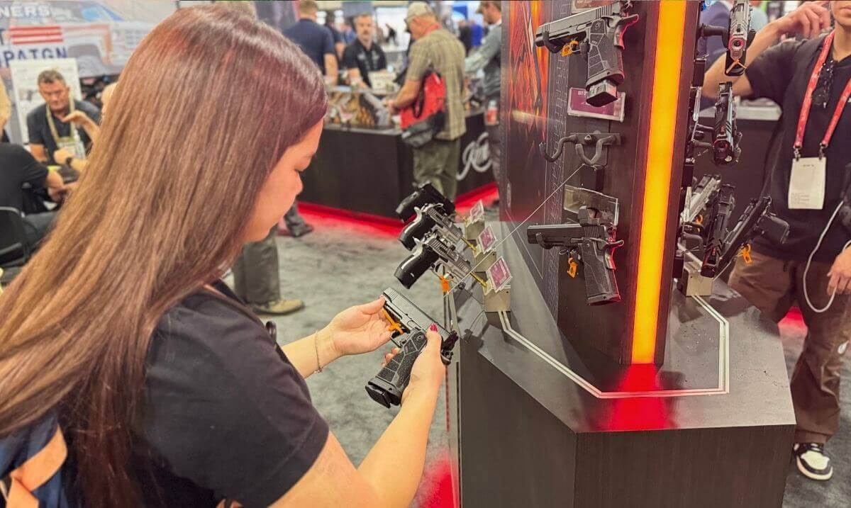 Array of new 2026 rifles including Sig MCX, Ruger Mini-14, and Daniel Defense ARs on a booth table with accessories and signage.